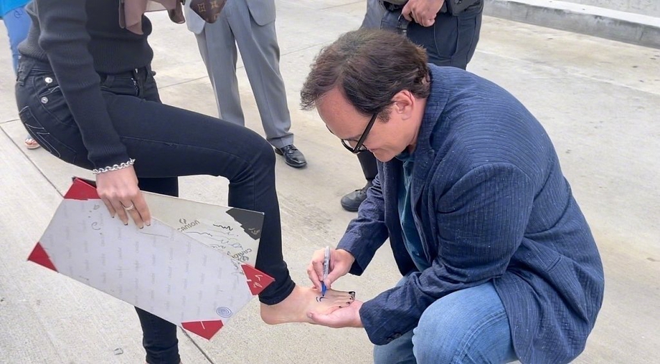 昆汀在女影迷脚上签名影迷开心抬脚展示